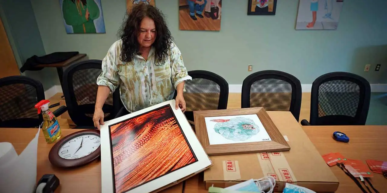 Nina Martinez hangs artwork by Seattle artist Jake Prendez on the walls of the Latino Civic Alliance’s new community center Wednesday in Burien. The LCA is sharing the space with Catholic Community Services in order to provide local Latino youth and their families with a range of services – from behavioral health care to social-emotional learning and leadership programs and classes – all in one location. Photo credit: Nicholas Johnson